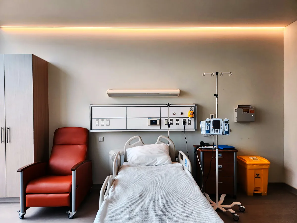 Private patient room with hospital bed, attendant recliner and bedside fittings