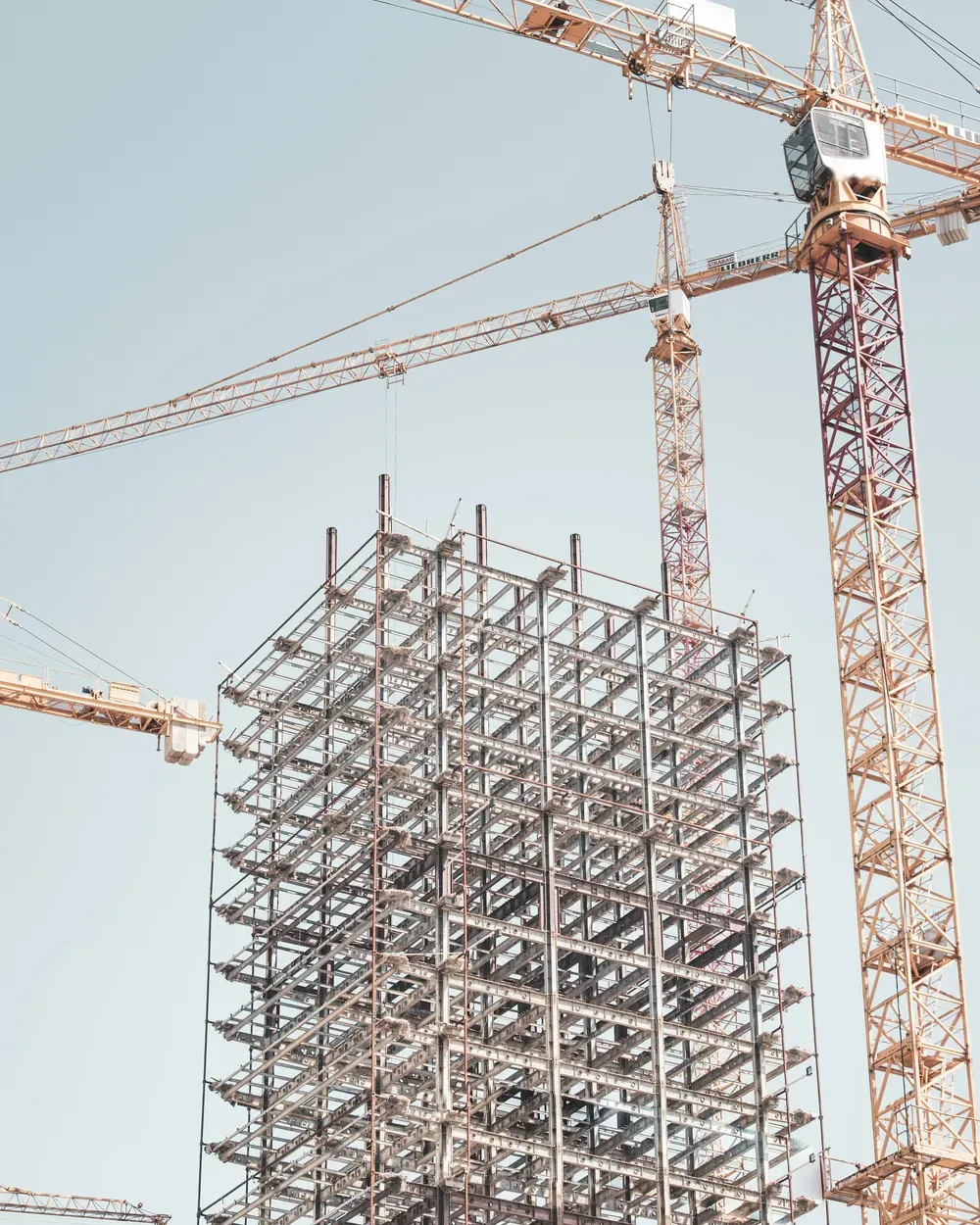 Tower crane beside a steel building frame on a construction site